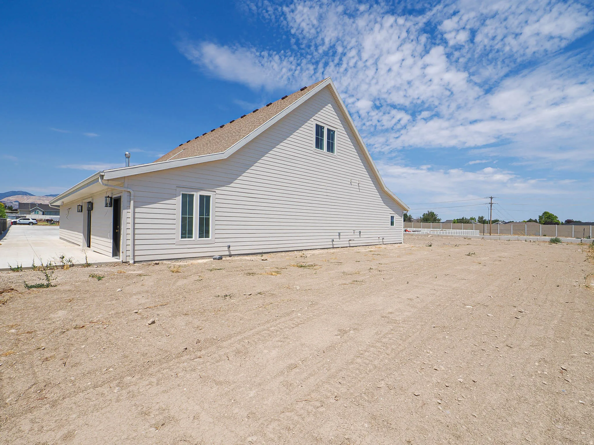 Newly constructed residence featuring light-colored siding and a brown shingle roof