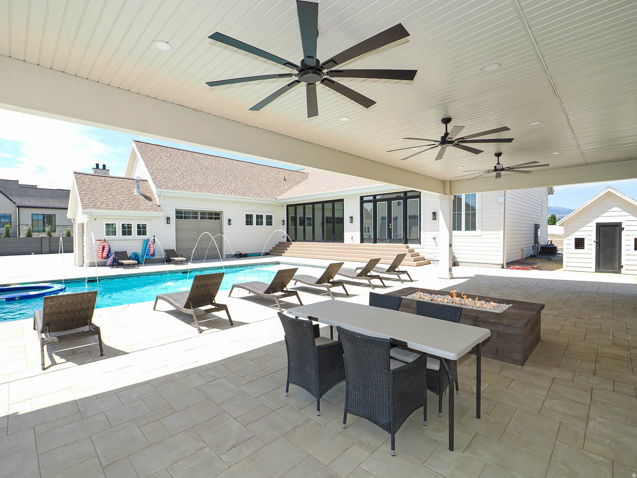 Expansive covered patio featuring multiple ceiling fans, recessed lighting, and a built-in fire pit