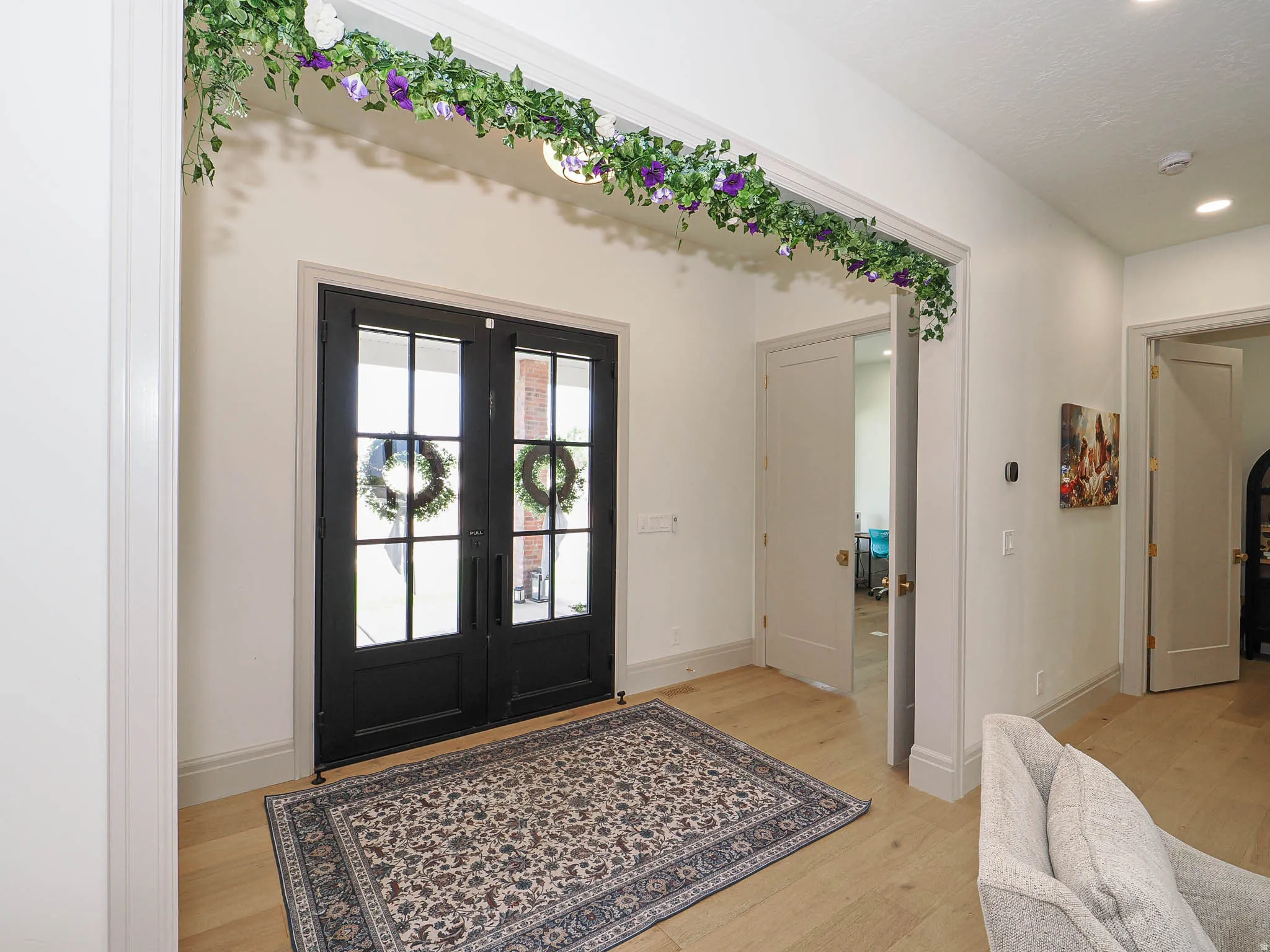 Entryway featuring double black French doors with transom windows, light wood-finish flooring, and recessed ceiling lighting