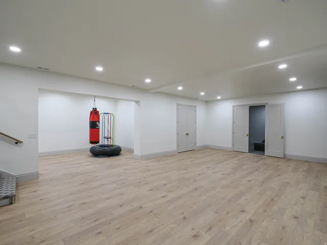 Spacious room featuring light wood-finish flooring, recessed lighting, white walls, and a substantial built-in alcove