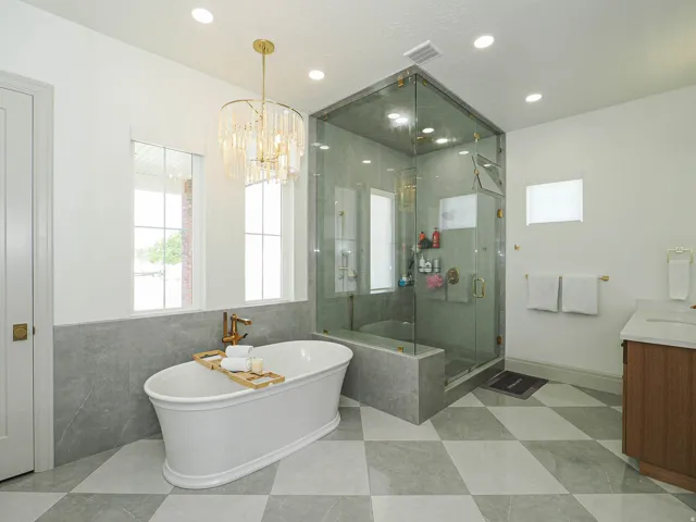 Freestanding soaking tub with gold-tone fixtures, complemented by a spacious glass-enclosed shower