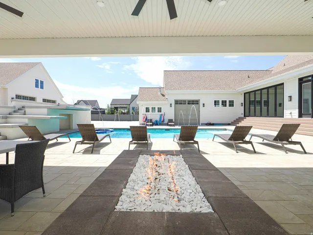 Expansive covered patio featuring a built-in fire pit, smooth ceiling with integrated fans, and a spacious paver stone surface