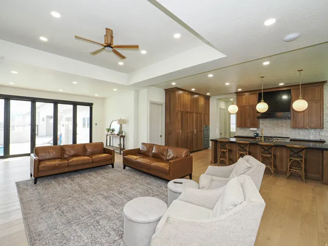Expansive open-concept living area featuring light wood-finish flooring, recessed lighting, and a modern ceiling fan