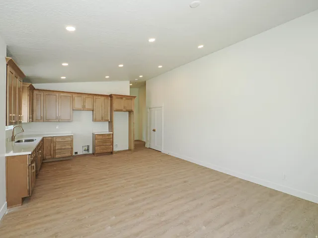 Open-concept living area with light wood-finish flooring, recessed lighting, and a white color palette