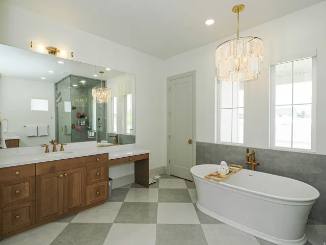 Freestanding soaking tub with floor-mounted fixture, checkered tile flooring, and a large vanity with dual sinks