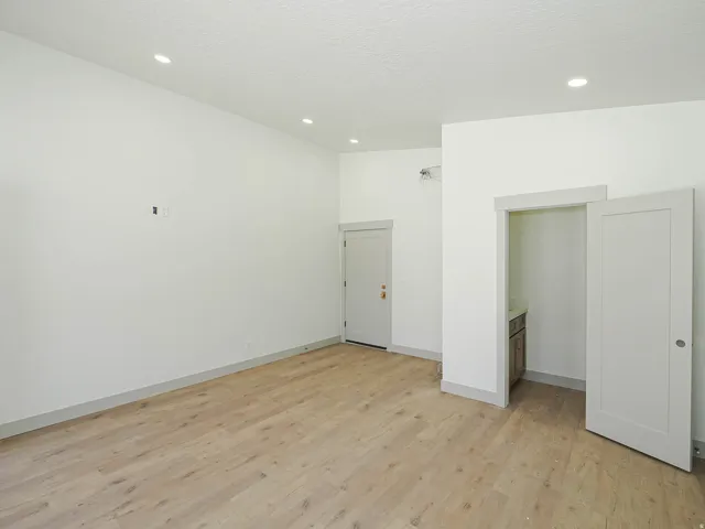 Open room featuring light wood-finish flooring, recessed ceiling lighting, and crisp white walls