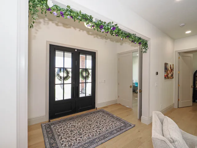 Entryway featuring double black French doors with transom windows, light wood-finish flooring, and recessed ceiling lighting