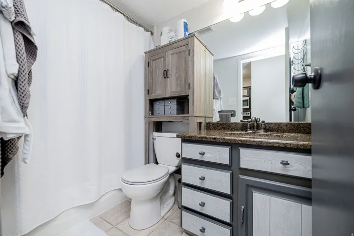 Bathroom featuring a vanity with a stone countertop, an integrated sink, and a wall-mounted mirror