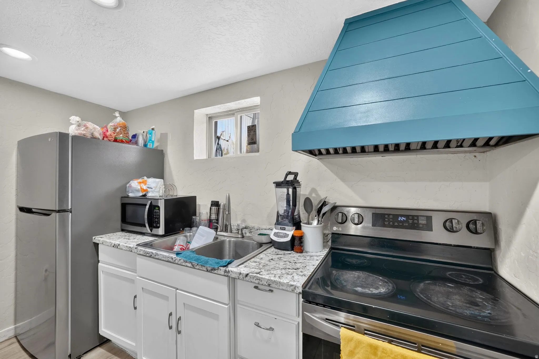 Second Kitchen featuring a distinct teal-colored range hood and stainless steel appliances and granite countertop