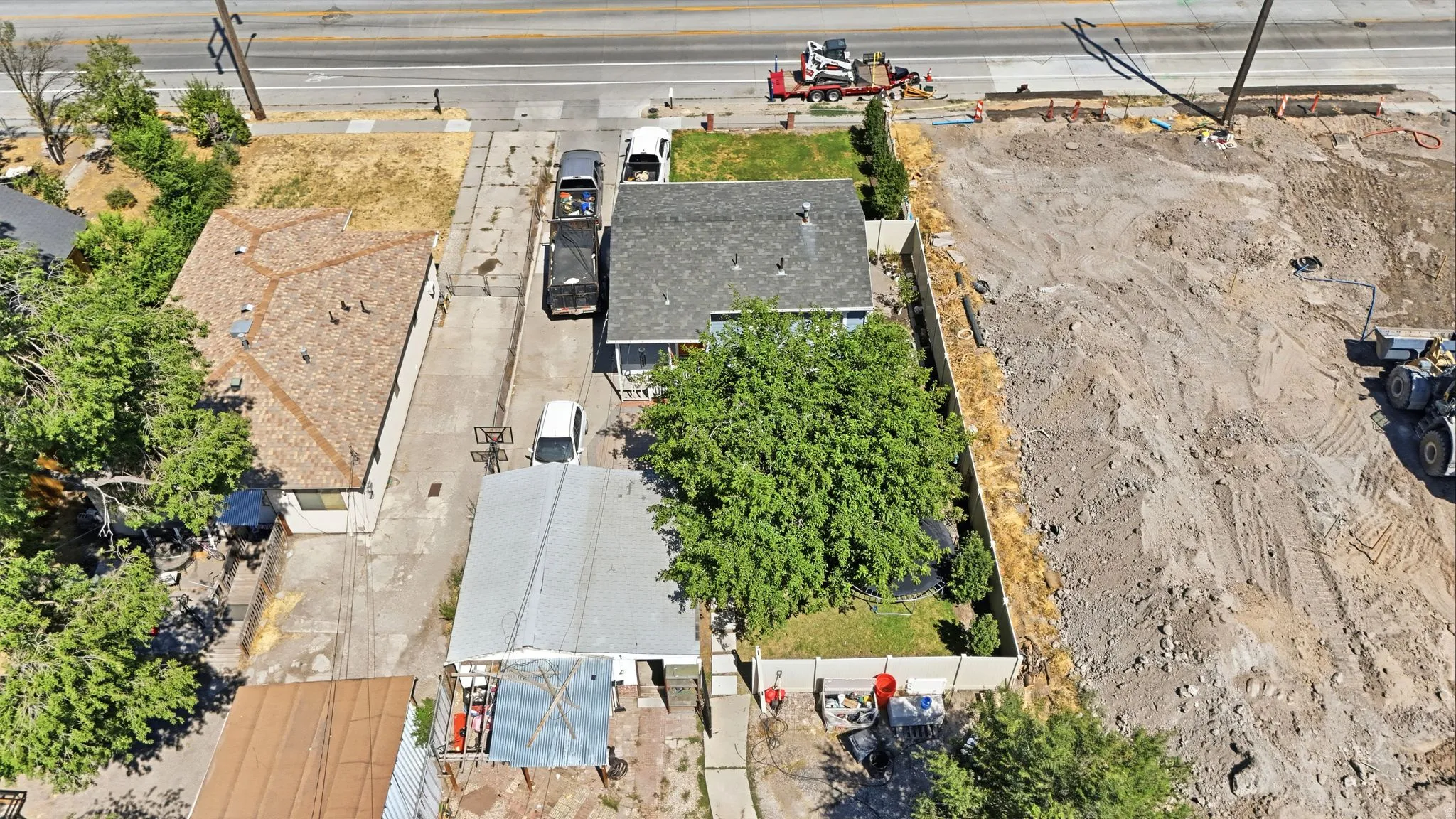 Aerial perspective highlighting the property with a well-maintained roof, paved driveway, and established tree