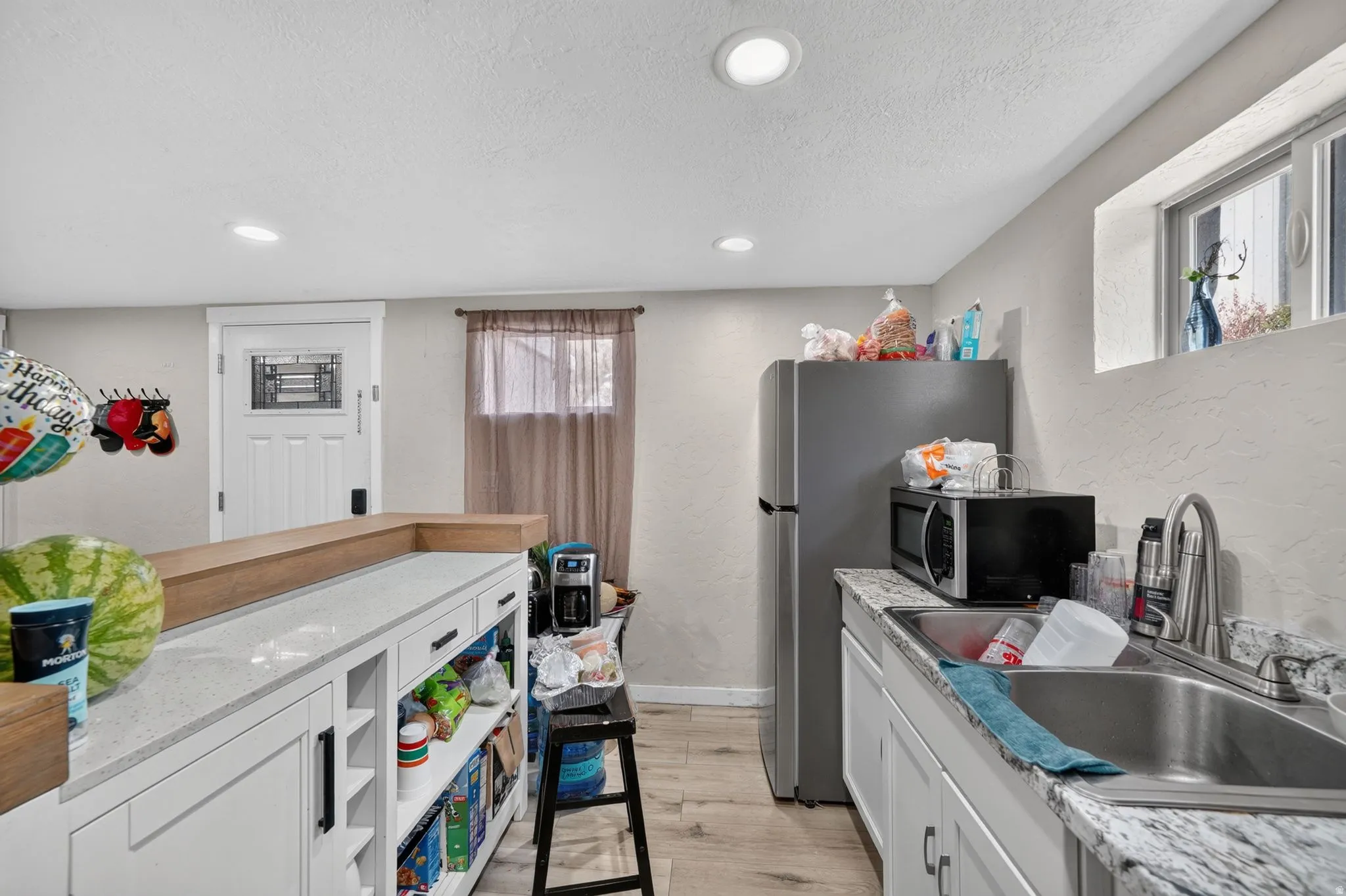 Compact kitchen featuring a stainless steel sink, light-toned countertops, and recessed lighting
