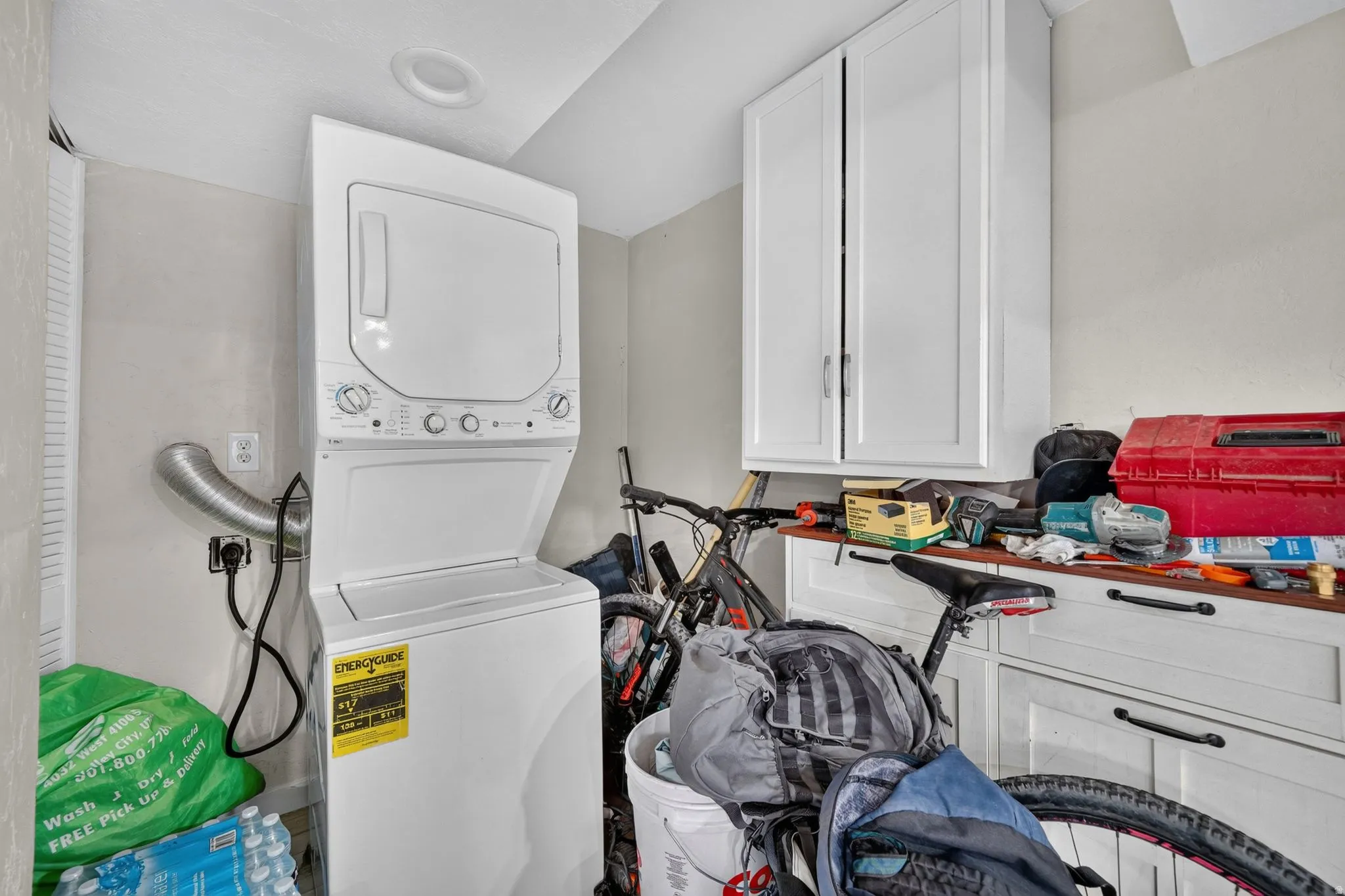 Laundry area featuring a stacked washer and dryer, recessed ceiling lighting, and overhead cabinetry
