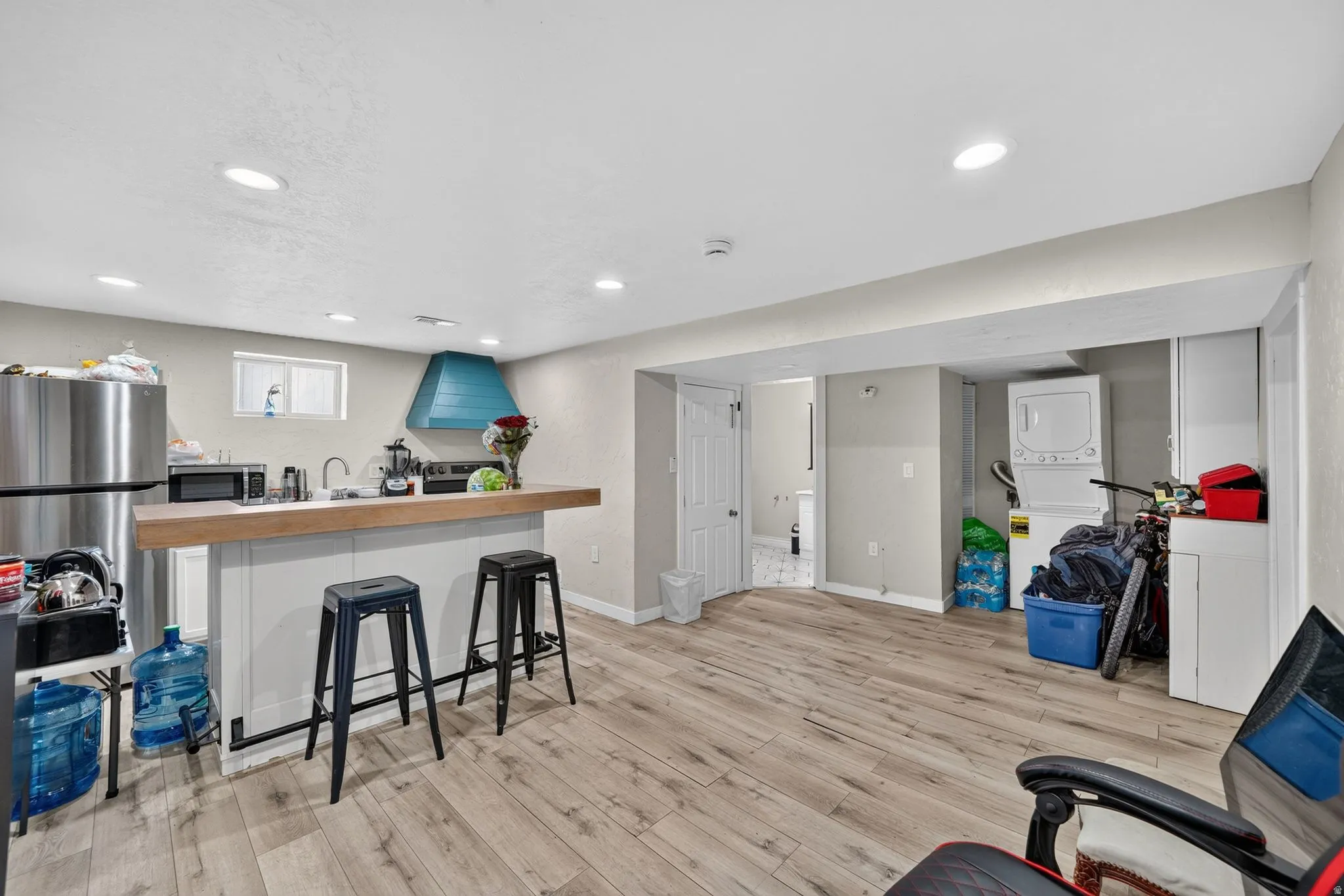 Open-concept living space featuring wood-finish flooring, recessed lighting, and a kitchen area with a wood-finish countertop island