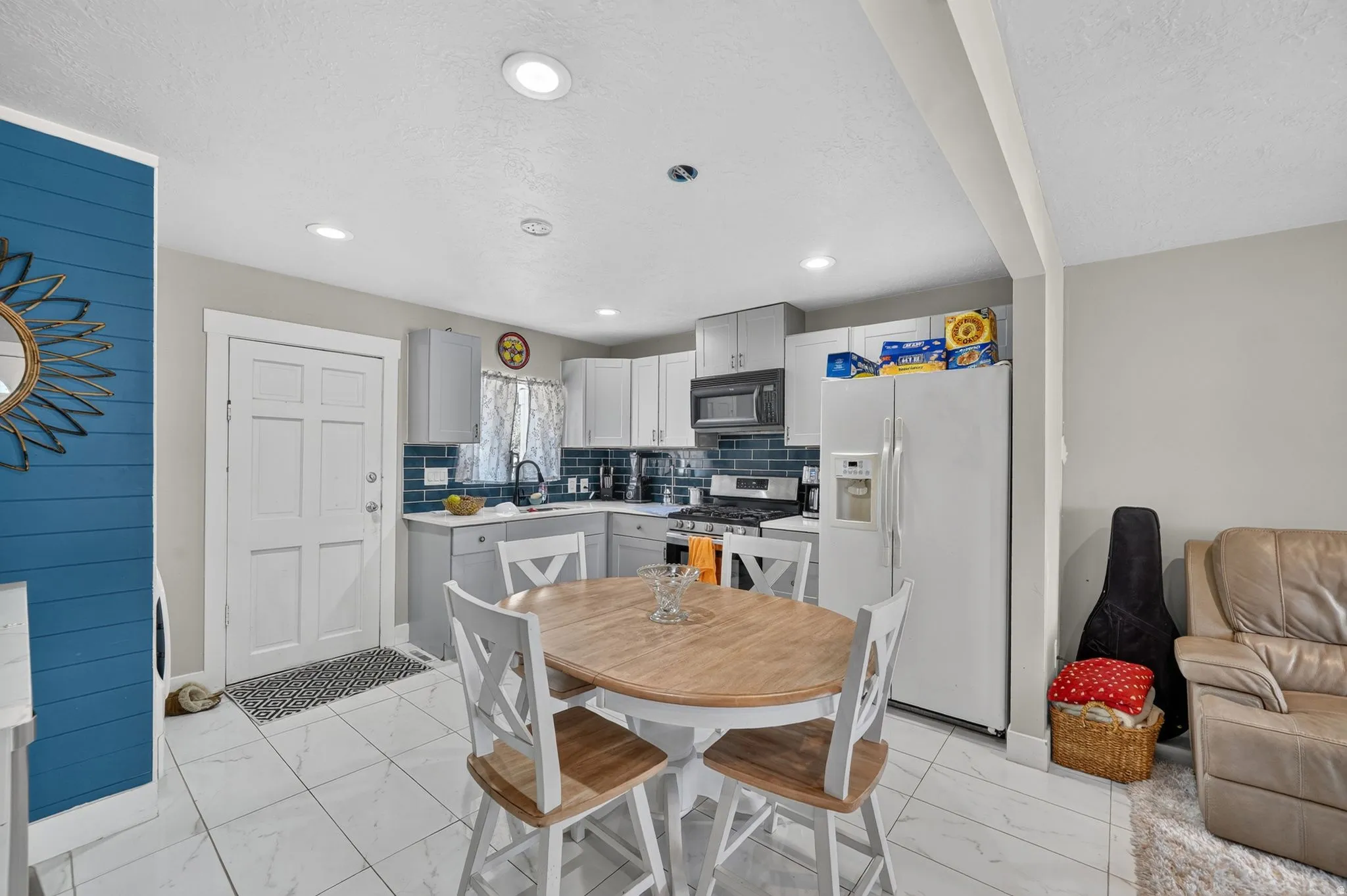 Kitchen featuring white tile flooring, gray cabinetry, and a dark blue subway tile backsplash