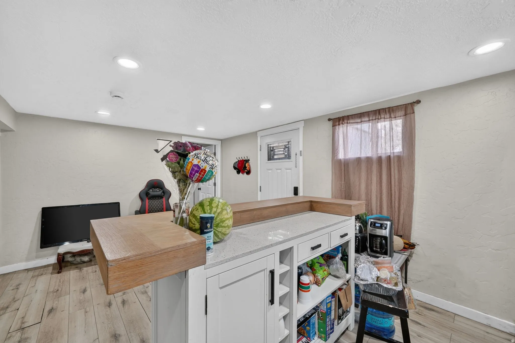 Kitchen island featuring a wood-finish breakfast bar, light granite countertop, and integrated storage with open shelving and cabinet doors