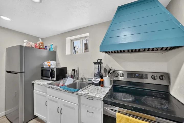 Second Kitchen featuring a distinct teal-colored range hood and stainless steel appliances and granite countertop