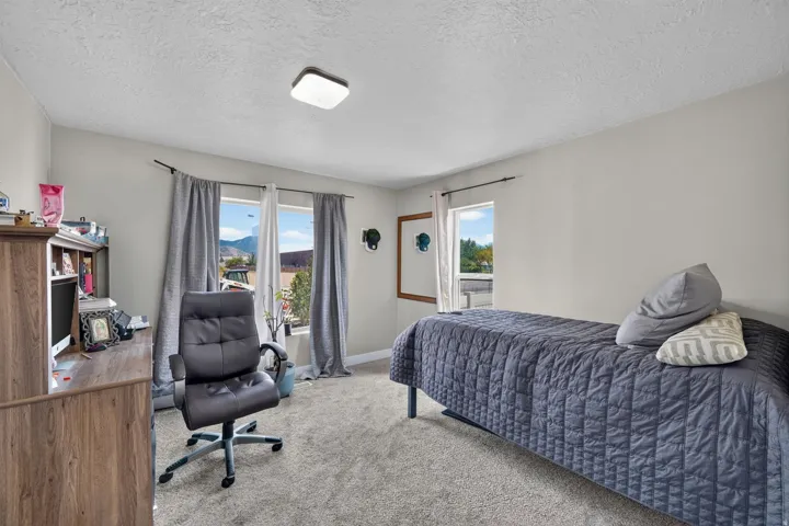 Carpeted room with multiple windows, presenting exterior mountain scenery