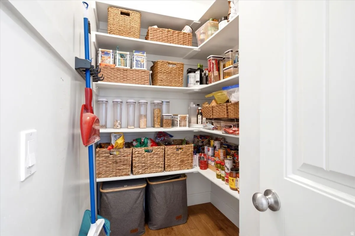 Extra-large walk-in pantry featuring white shelving, wood-finish flooring, and ample storage space