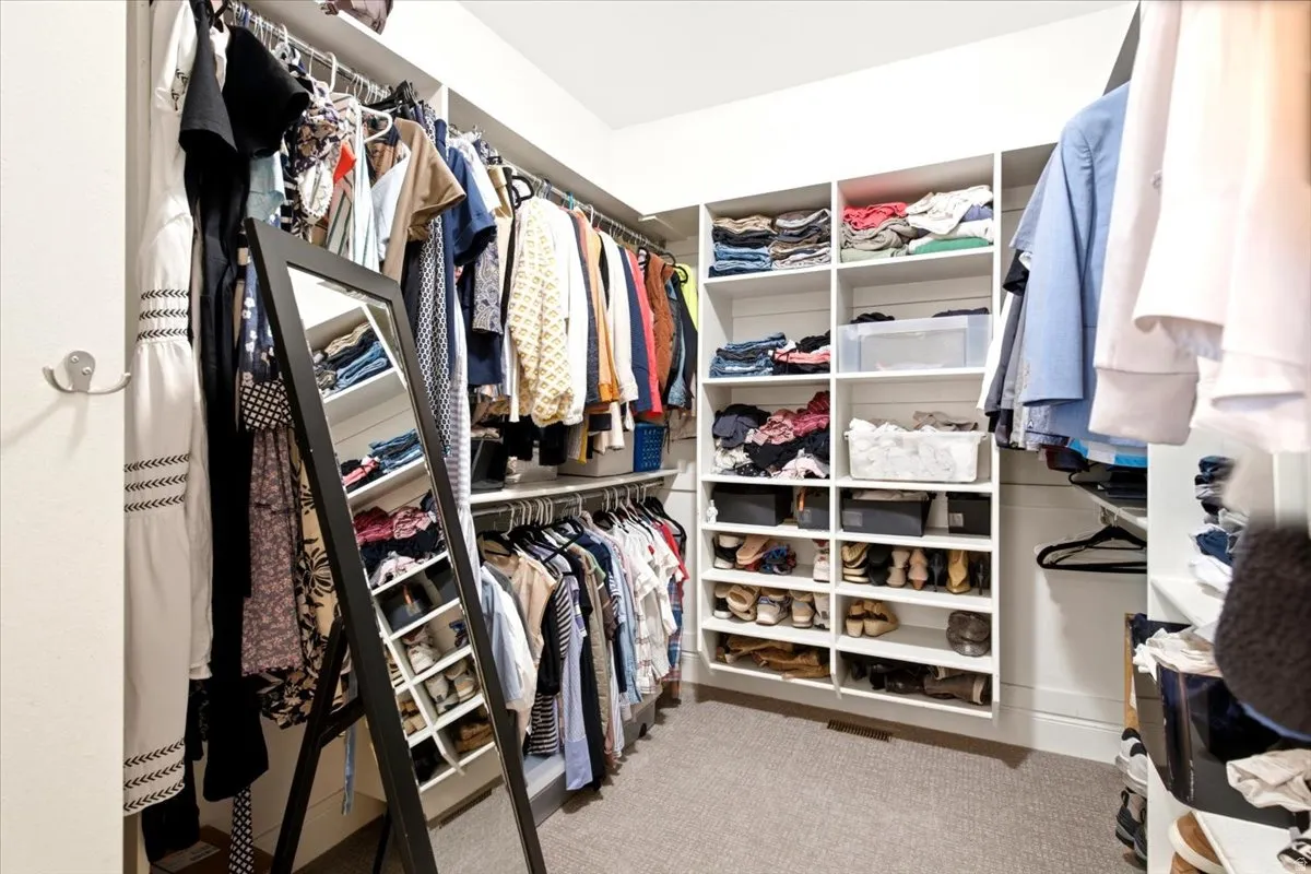 Customizable walk-in closet featuring built-in shelving, hanging rods, and carpet flooring