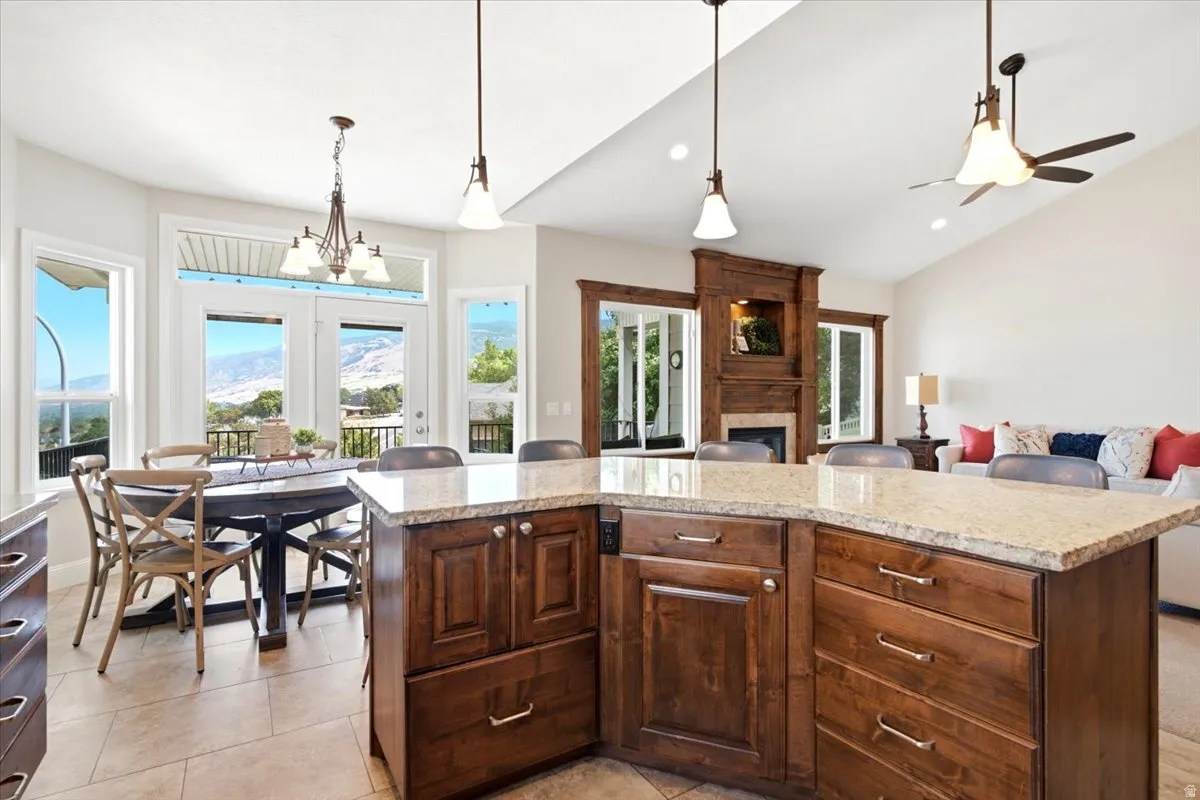 Open-concept interior featuring a substantial kitchen island with a light-toned countertop, rich wood-finish cabinetry, and contemporary pendant lighting