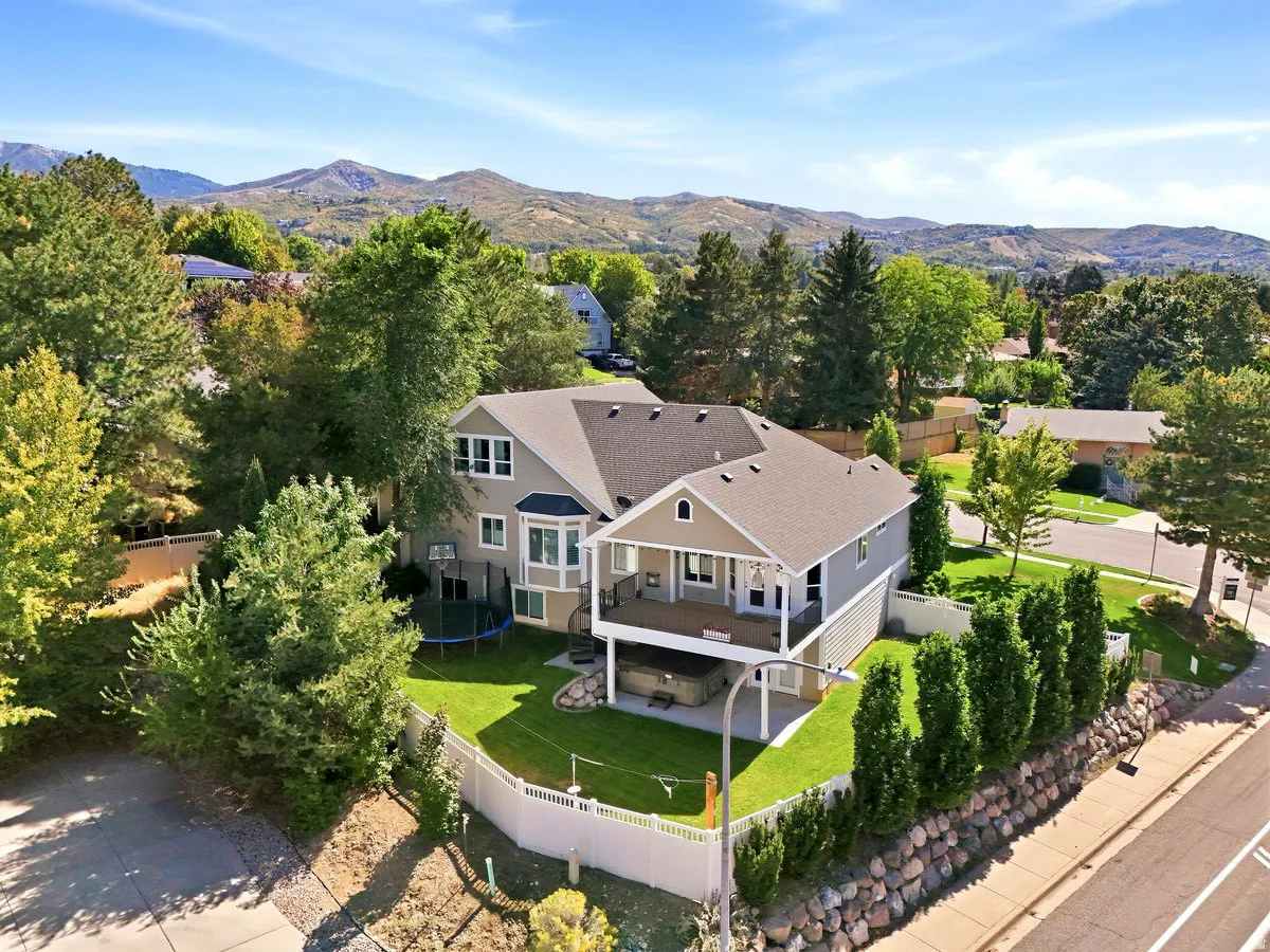 Multi-level dwelling with a covered upper deck, a lower-level patio, and a manicured lawn