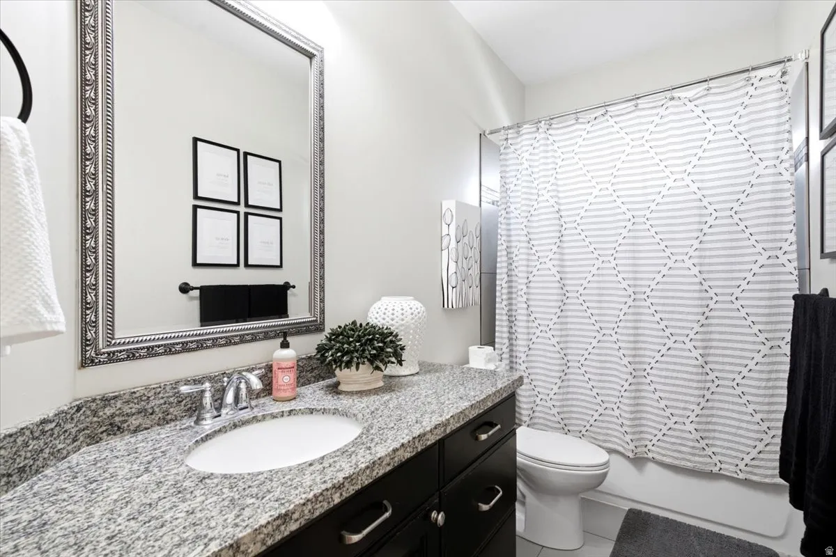 Bathroom featuring a spacious vanity with a granite countertop, undermount sink, and dark wood cabinetry