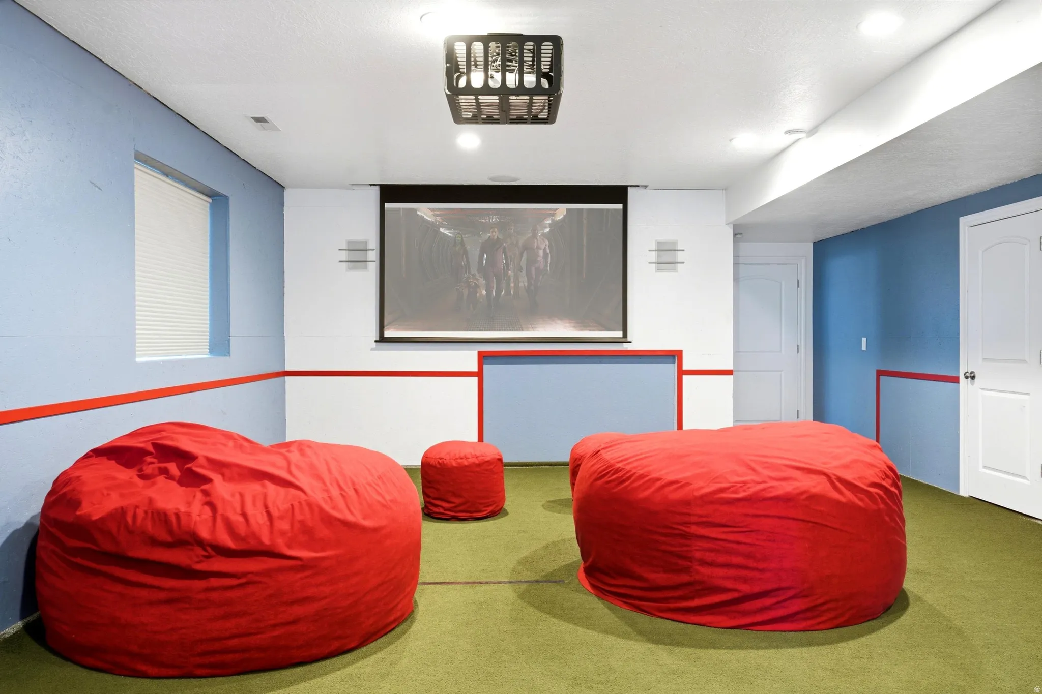 Recreational room featuring a mounted projector screen, recessed lighting, and a window with blinds