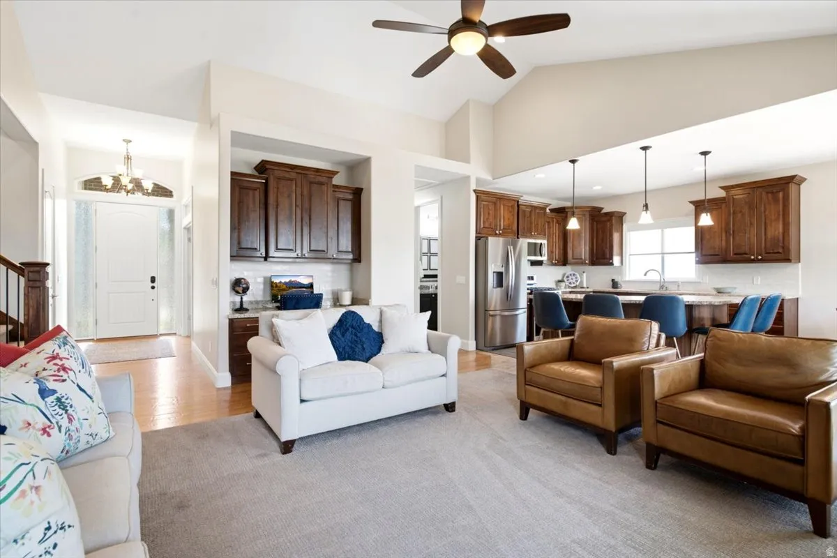 Open concept living area featuring vaulted ceilings, wood-finish flooring, and a ceiling fan