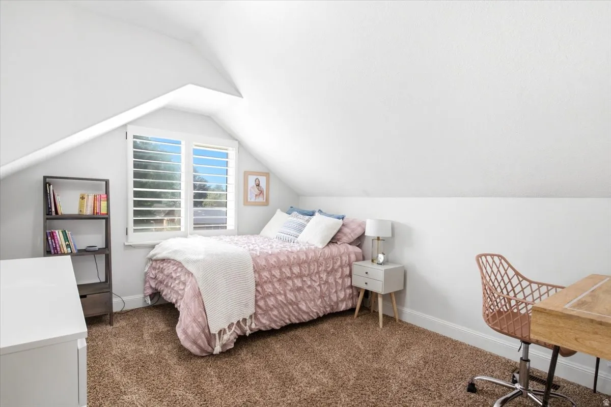 Attic room with sloped ceilings, carpet flooring, a multi-pane window with louvered shutters, and white baseboards