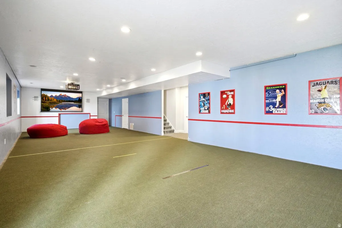 Recessed lighting, light-colored walls, green carpeting, white trim, and a built-in projection screen