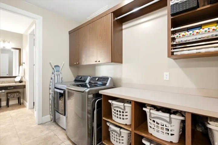 Main-level laundry area featuring upper cabinetry, a hanging rod, and built-in shelving with a countertop workspace
