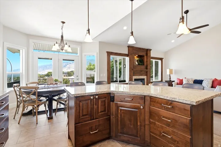 Open-concept interior featuring a substantial kitchen island with a light-toned countertop, rich wood-finish cabinetry, and contemporary pendant lighting