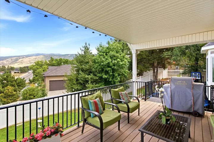 Covered deck featuring wood-finish flooring, black metal railing, and a slatted ceiling