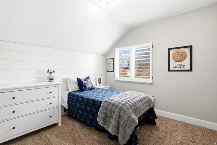 Bedroom featuring great lighting, neutral carpeting, and a window with plantation shutters