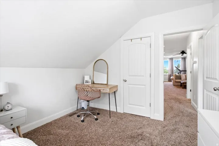 Room featuring angled white walls, brown textured carpeting, and white baseboards