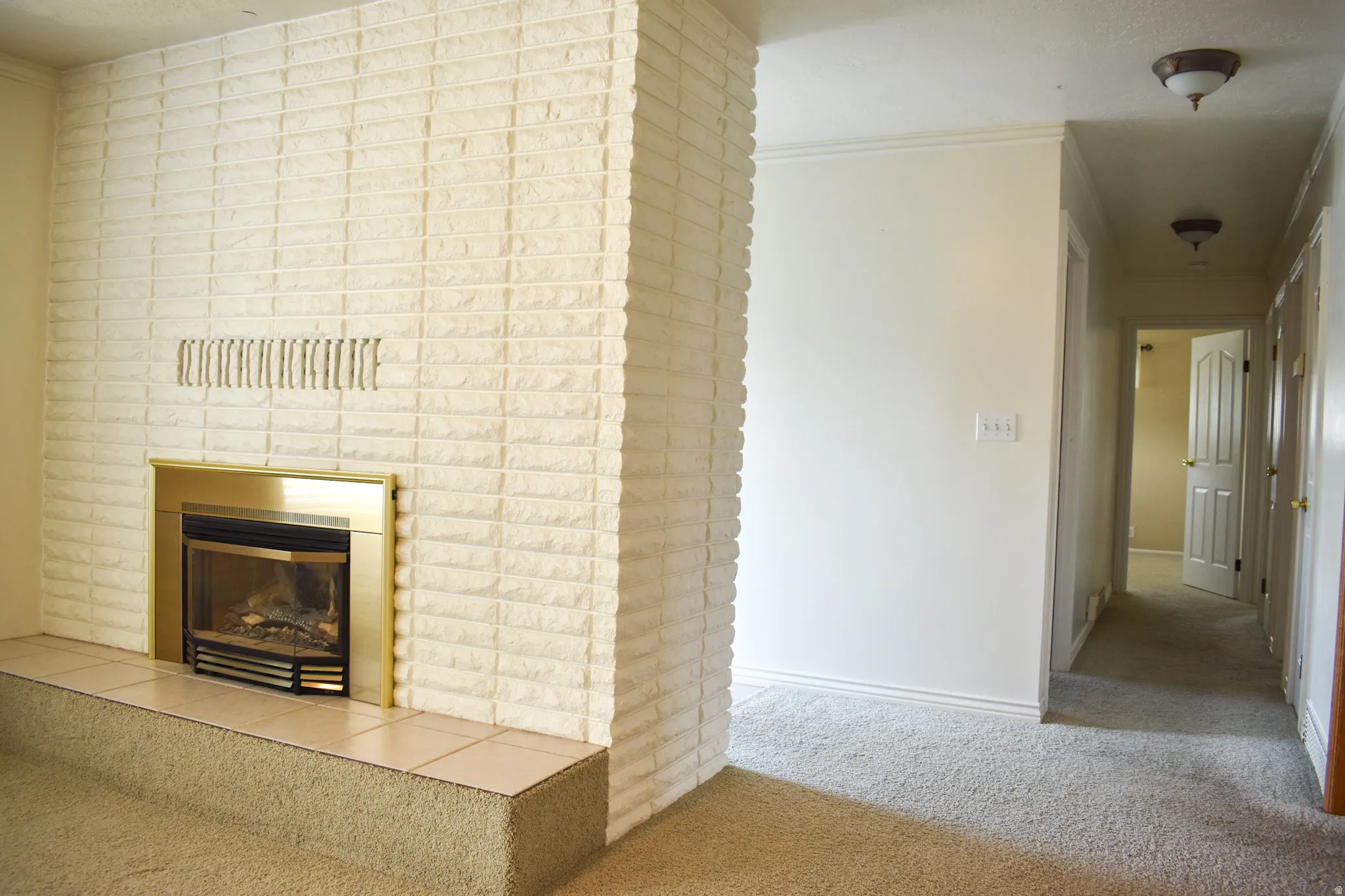 White-painted brick fireplace with a gold-toned insert and raised hearth