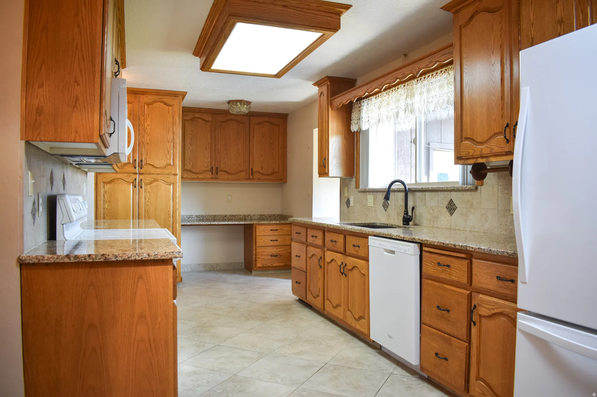 Kitchen featuring wood-finish cabinetry, stone countertops, and tile flooring