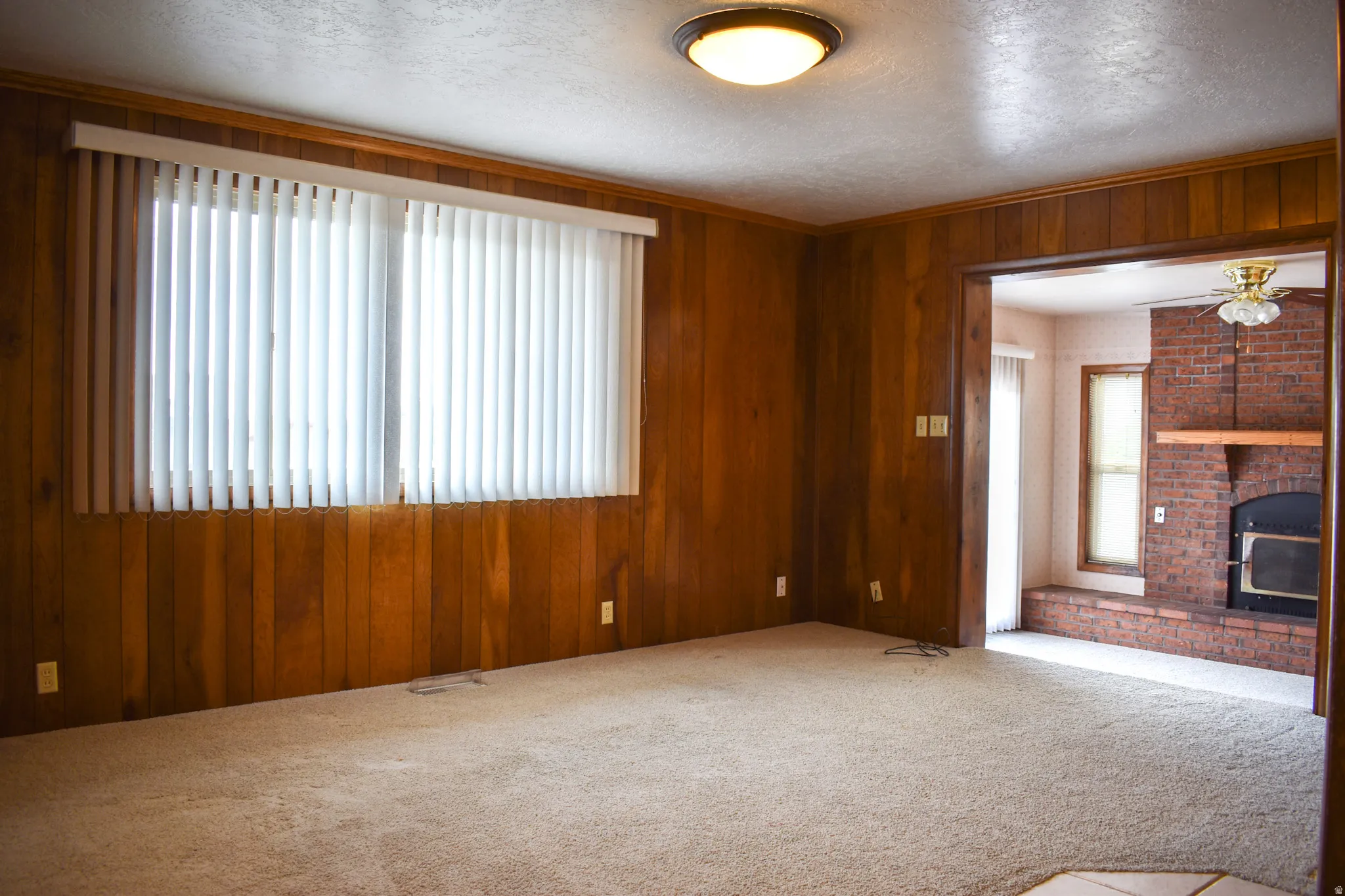 Spacious room with wood paneling walls and neutral-toned carpeting
