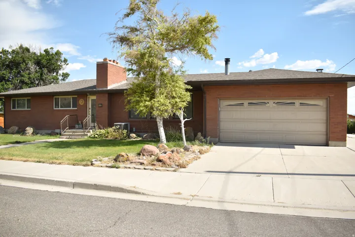 Brick ranch-style residence featuring a prominent front-facing two-car garage with a decorative panel door