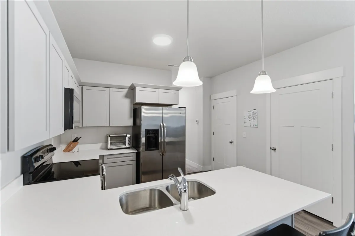 Modern kitchen island featuring a double stainless steel sink, chrome faucet, and pendant lighting
