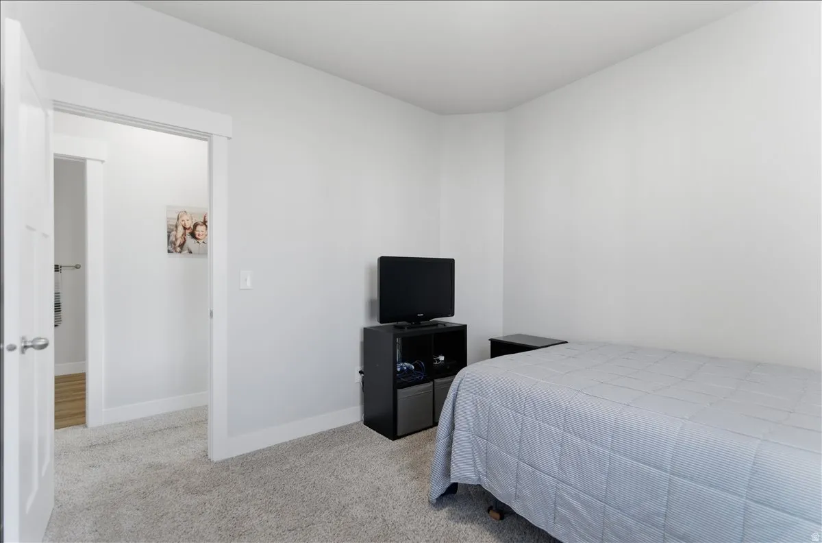 Carpeted room with light gray walls, white trim, and a white interior door
