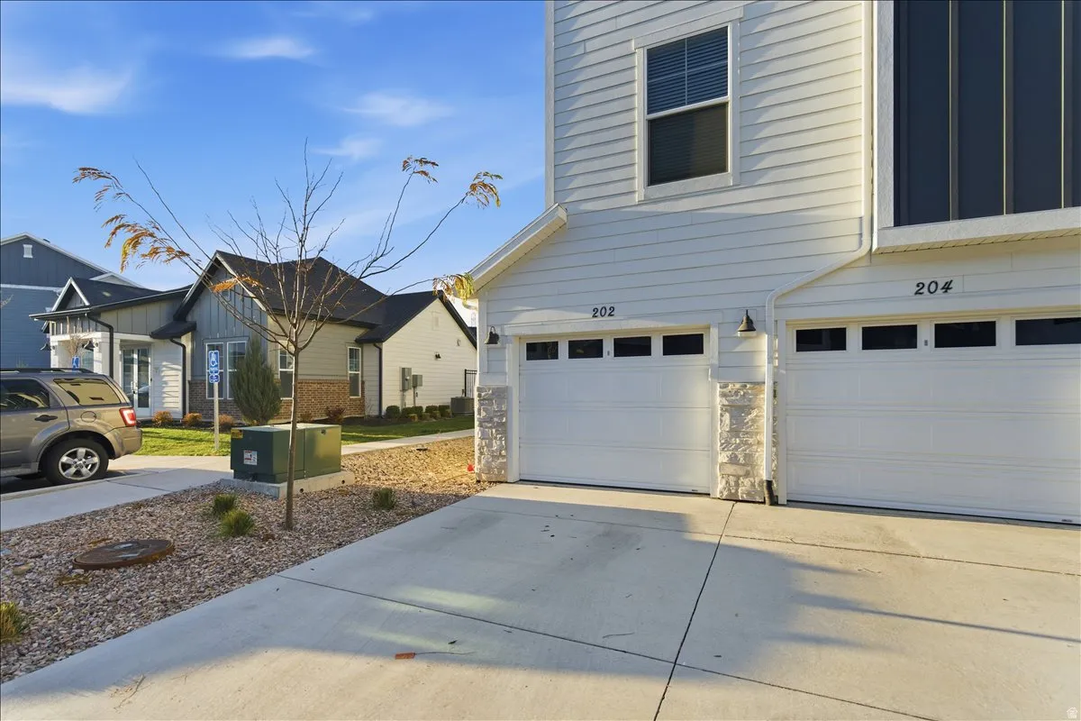 White vinyl siding exterior with stone accents, featuring two attached garages with individual driveways and transom windows