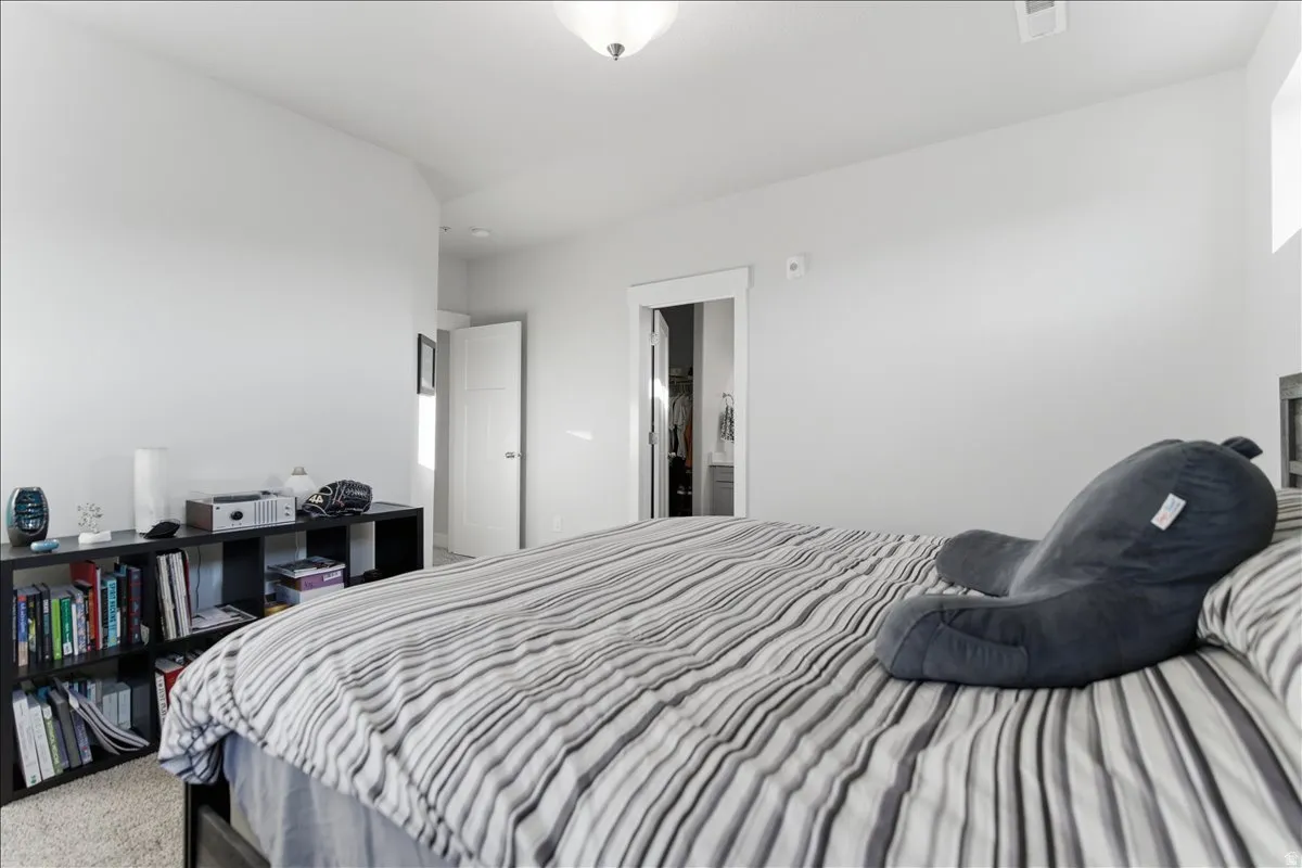 Spacious bedroom featuring light-colored walls and carpet flooring