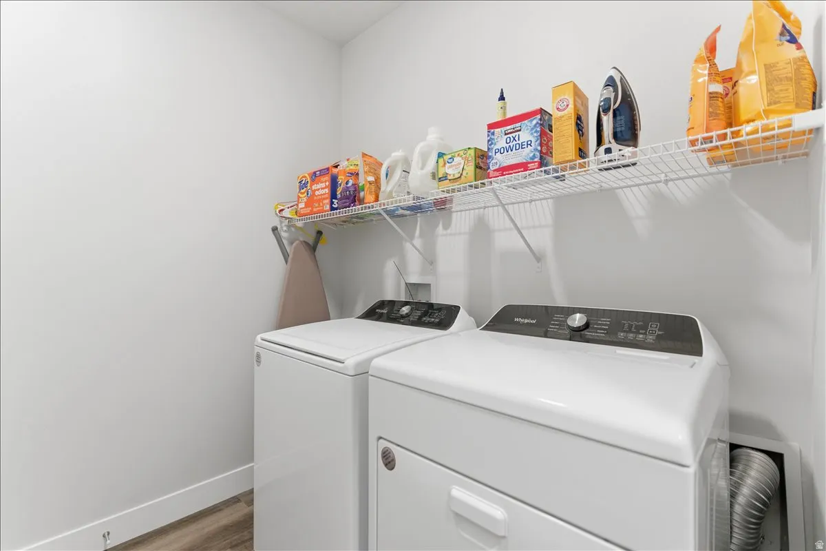 Dedicated laundry area featuring a white wire shelving unit, wood-finish flooring, and crisp white walls