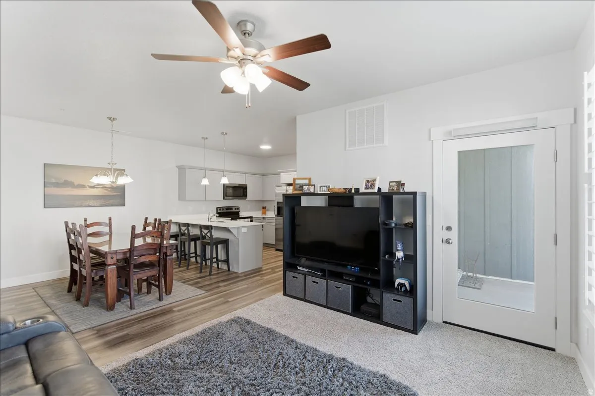 Open-concept living space featuring wood-finish flooring, a contemporary ceiling fan, and a glass-paned door