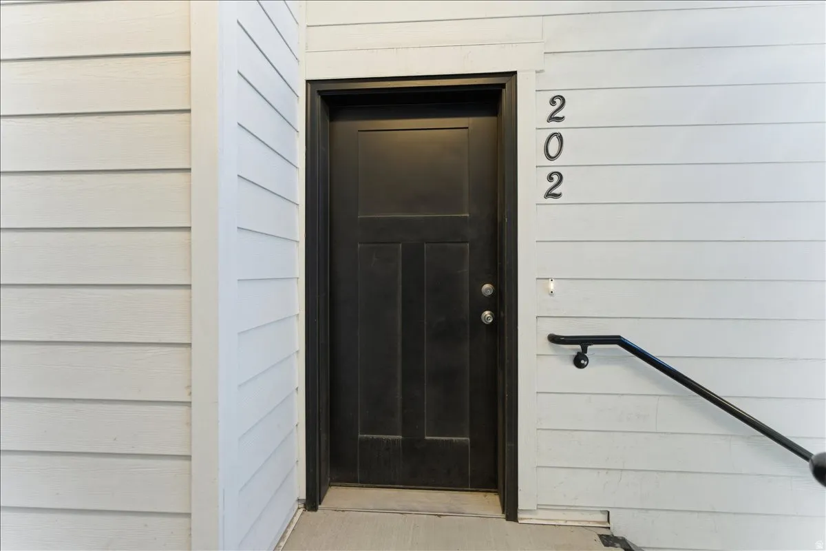 Black paneled entry door with silver hardware, complemented by light-toned horizontal siding