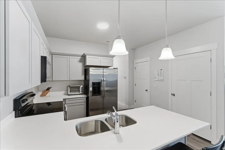 Modern kitchen island featuring a double stainless steel sink, chrome faucet, and pendant lighting