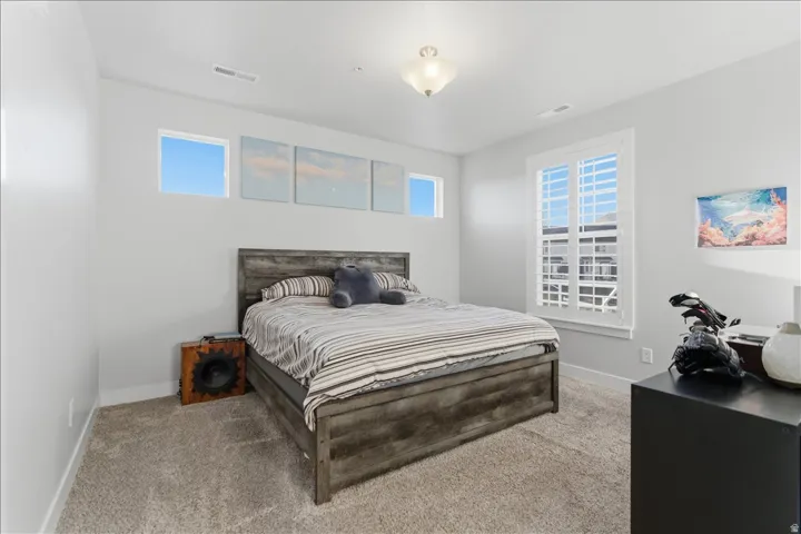 Spacious room with light gray walls, plush carpet, and white plantation shutters on a large window