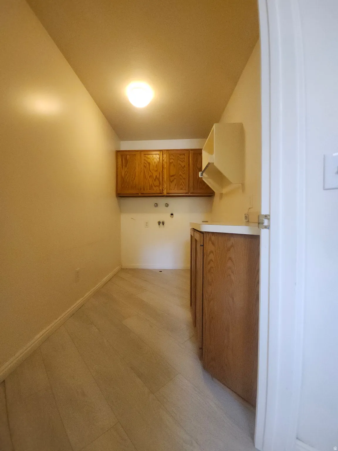 Full Laundry room by kitchen and garage Entrance, Wood-finish flooring, overhead built-in cabinetry, and built-in countertop with lower cabinetry