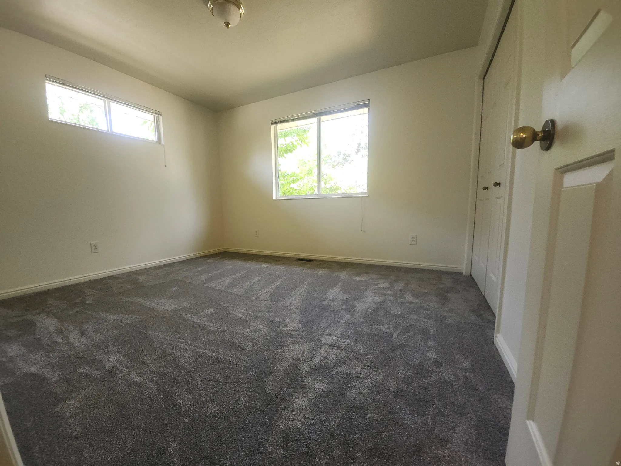 3rd Bedroom upstairs. Bright secondary bedroom featuring neutral wall finishes, dual windows with natural light, new carpeting in charcoal gray tones, and direct access to hallway entry
